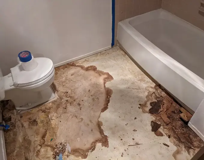 Water-stained bathroom subfloor exposed beside a toilet and tub in Dublin, CA